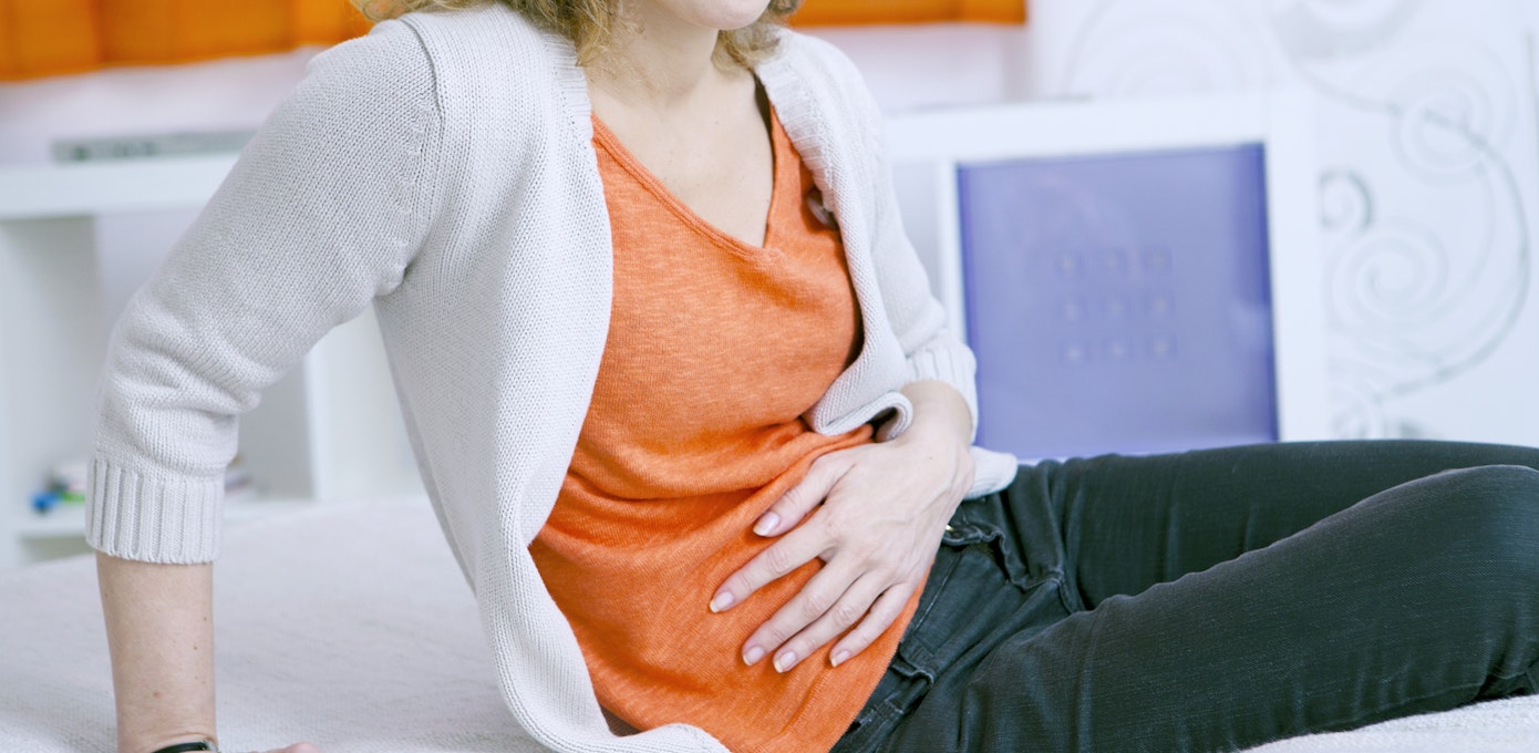 An image depicting a person suffering from dull abdominal pain symptoms